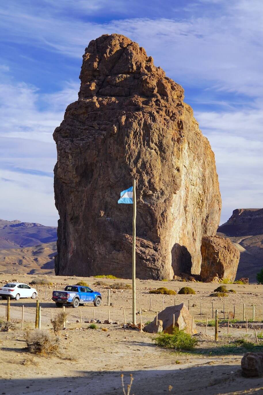 Monolito de Piedra Parada con la bandera argentina y vehículos al pie